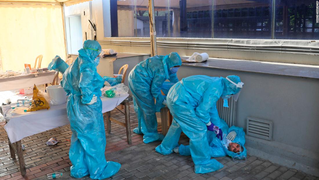 Health workers at a coronavirus testing center in New Delhi attend to a colleague who fainted due to exhaustion on April 27. 